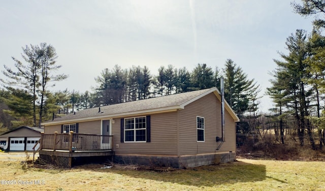 view of front of home with a deck, an outbuilding, and a front lawn