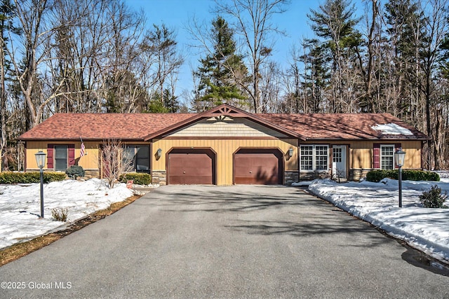 view of front facade with aphalt driveway, stone siding, and a garage