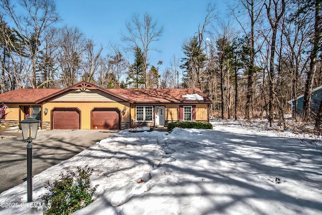 view of front facade with an attached garage, stone siding, and driveway