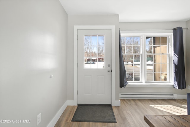 doorway to outside featuring a baseboard heating unit, baseboards, and wood finished floors