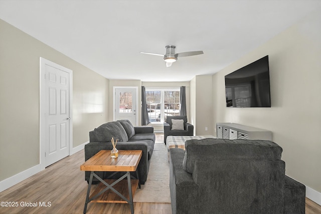 living room with ceiling fan, baseboards, and wood finished floors