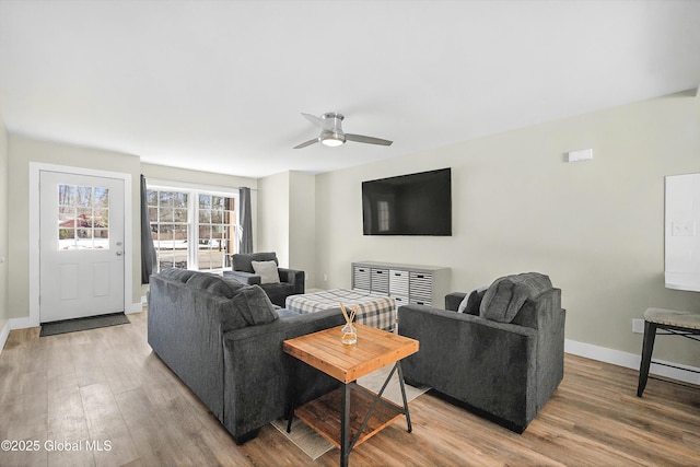 living area with a ceiling fan, light wood-type flooring, and baseboards