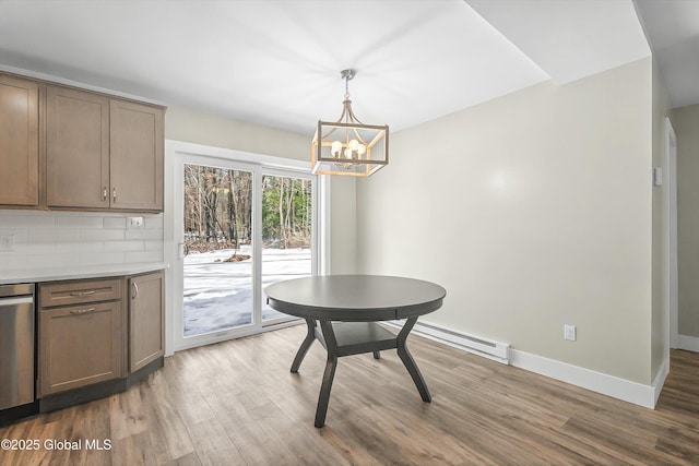 dining space featuring a notable chandelier, wood finished floors, baseboards, and a baseboard radiator