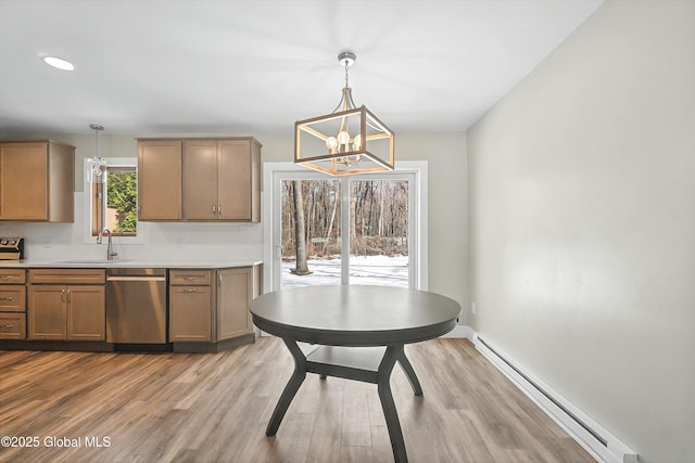 dining space with light wood-type flooring, a baseboard radiator, baseboards, and a notable chandelier