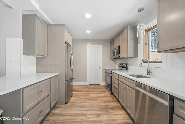 kitchen with light wood finished floors, a sink, light countertops, appliances with stainless steel finishes, and tasteful backsplash