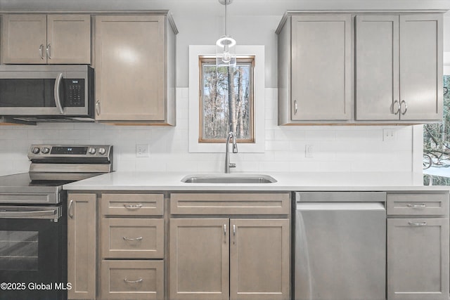 kitchen featuring a sink, backsplash, appliances with stainless steel finishes, and light countertops