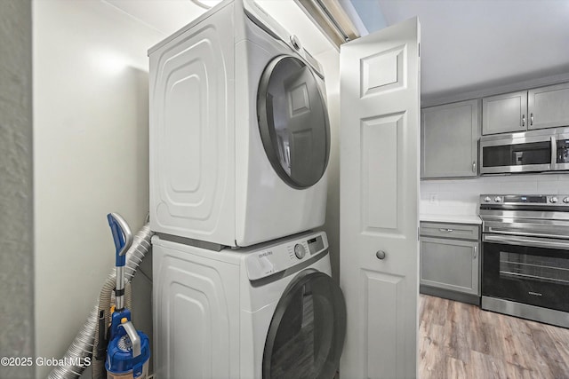 laundry room with laundry area, stacked washer / dryer, and light wood-style flooring