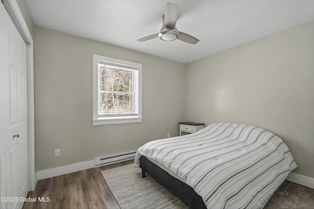 bedroom with wood finished floors, baseboards, a ceiling fan, a closet, and a baseboard heating unit