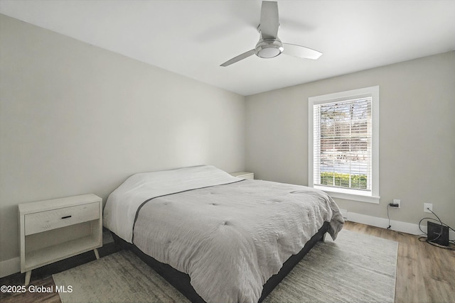 bedroom featuring baseboards, wood finished floors, and a ceiling fan