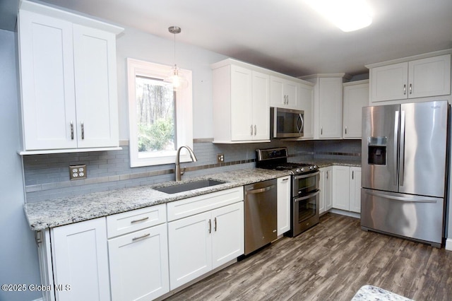 kitchen featuring a sink, backsplash, dark wood finished floors, stainless steel appliances, and white cabinets