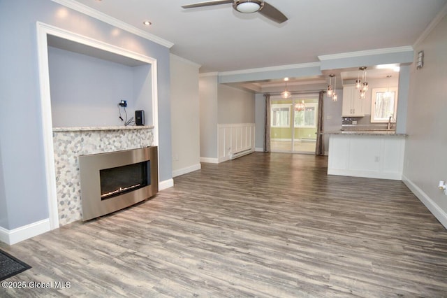 unfurnished living room with ornamental molding, wood finished floors, a fireplace, baseboards, and ceiling fan