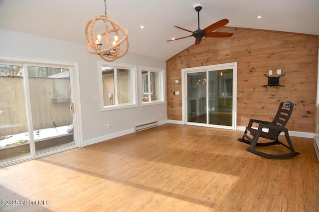 interior space with baseboards, wood walls, lofted ceiling, wood finished floors, and a baseboard radiator