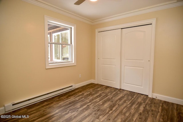 unfurnished bedroom featuring ornamental molding, a baseboard heating unit, dark wood finished floors, a closet, and baseboards