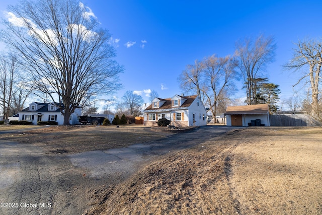 new england style home featuring a garage, an outbuilding, and fence