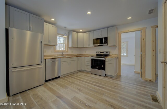 kitchen featuring visible vents, stainless steel appliances, wood counters, and a sink