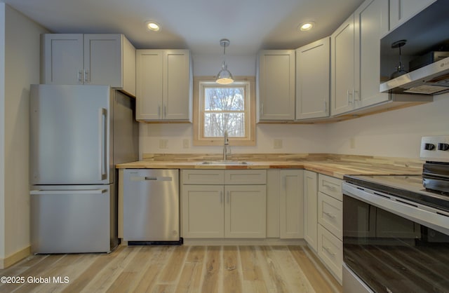 kitchen featuring a sink, stainless steel appliances, butcher block counters, and light wood finished floors