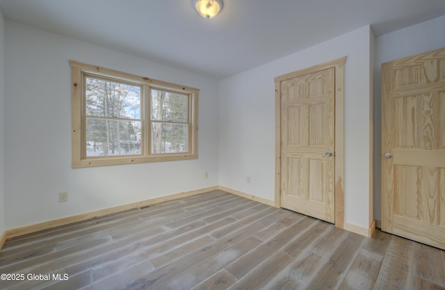 unfurnished bedroom featuring wood finished floors and baseboards