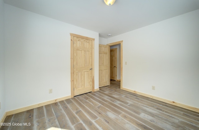 spare room featuring baseboards and wood finished floors