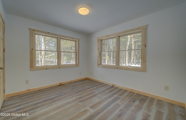 spare room featuring baseboards and wood finished floors