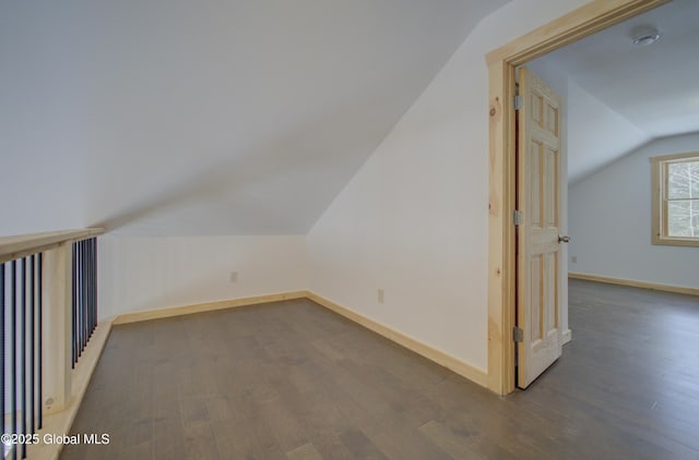 additional living space with dark wood-style floors, lofted ceiling, and baseboards