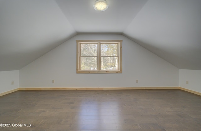 additional living space with baseboards, wood finished floors, and vaulted ceiling