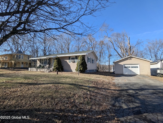 view of front of property with an outbuilding, a detached garage, aphalt driveway, and a front yard