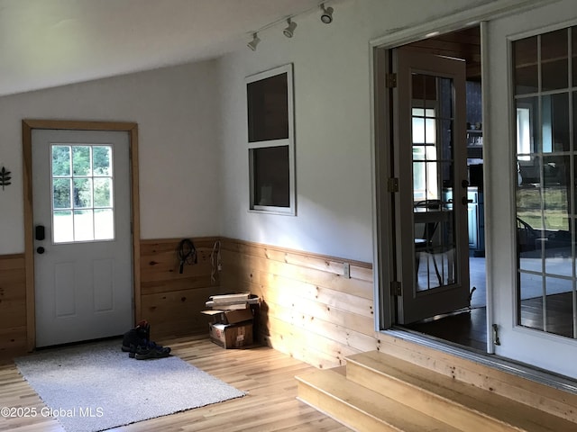 doorway with wainscoting, wood walls, and wood finished floors