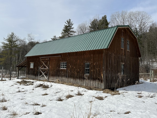 snow covered structure with an outbuilding