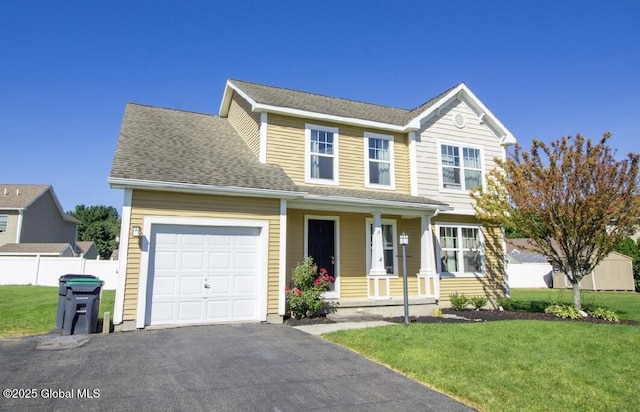 traditional home featuring driveway, fence, covered porch, an attached garage, and a front yard