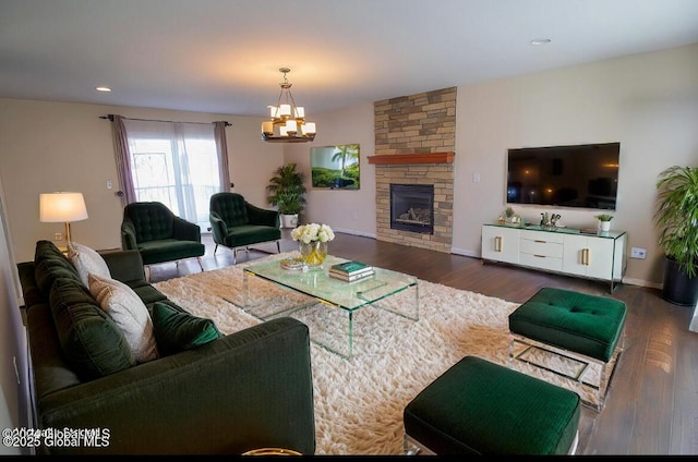 living room with wood finished floors, baseboards, an inviting chandelier, recessed lighting, and a stone fireplace