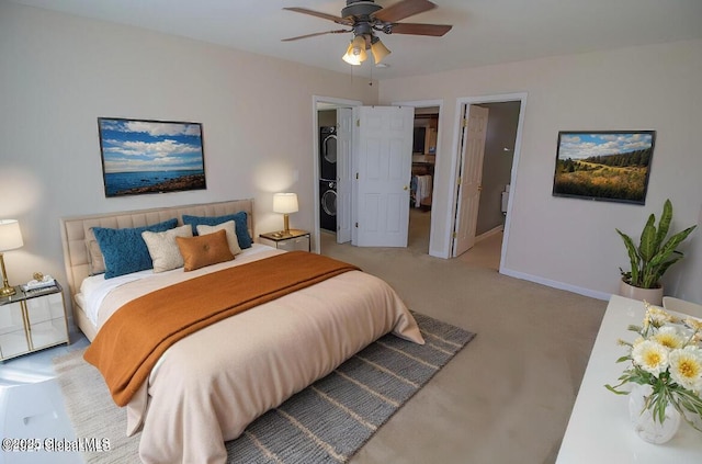 bedroom with a walk in closet, light carpet, stacked washer and dryer, a ceiling fan, and baseboards