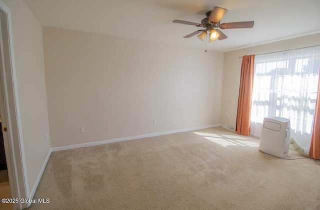 spare room featuring ceiling fan, baseboards, and light carpet