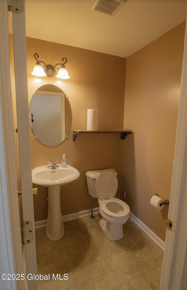 half bath with visible vents, baseboards, and toilet