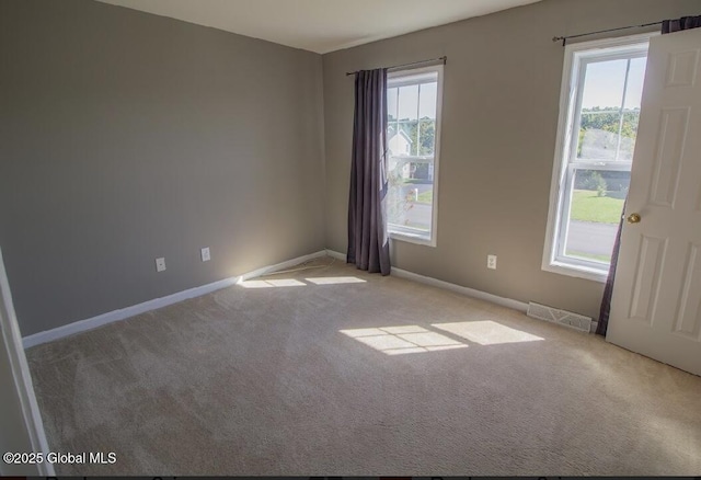 empty room featuring carpet, visible vents, and baseboards