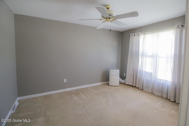 empty room featuring a ceiling fan, baseboards, and light carpet