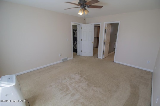 unfurnished bedroom with baseboards, visible vents, stacked washer and clothes dryer, and light carpet