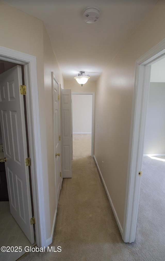 hallway featuring light carpet and baseboards