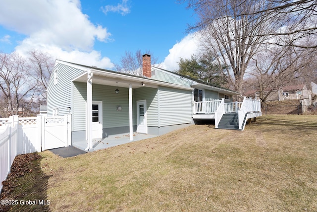 back of house with fence, a wooden deck, a chimney, a yard, and a gate