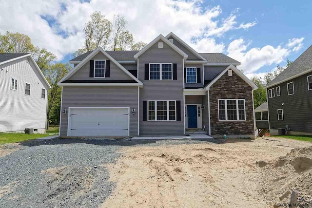 view of front of house with a garage, stone siding, and driveway