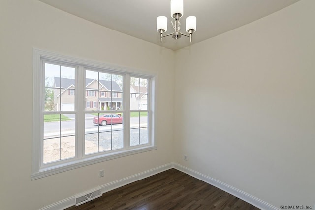 empty room with dark wood-style floors, visible vents, an inviting chandelier, and baseboards