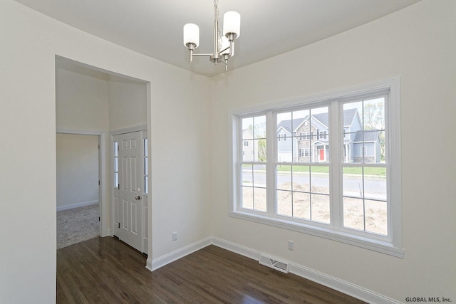 spare room with dark wood finished floors, visible vents, a chandelier, and baseboards