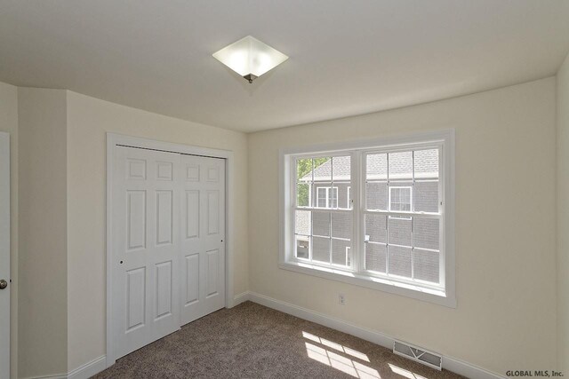 unfurnished bedroom with visible vents, baseboards, carpet, and a closet