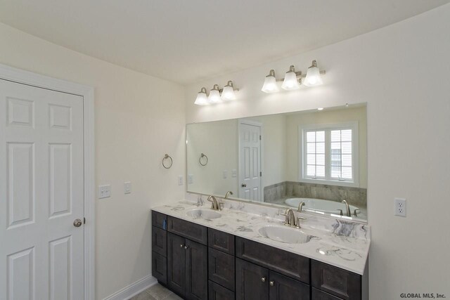 bathroom featuring double vanity, a bath, baseboards, and a sink