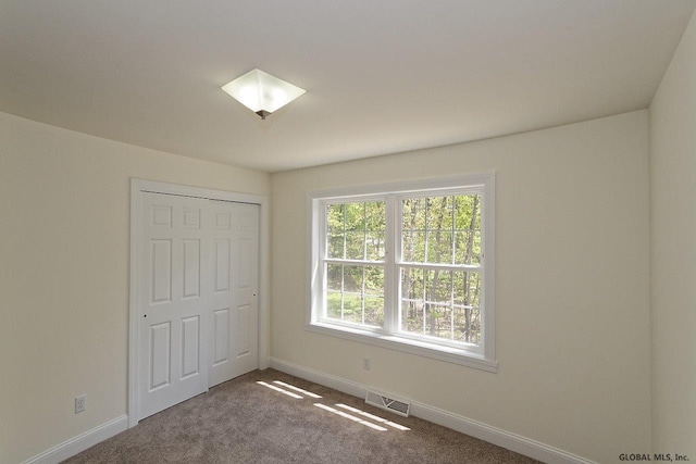 unfurnished bedroom with visible vents, baseboards, a closet, and carpet flooring