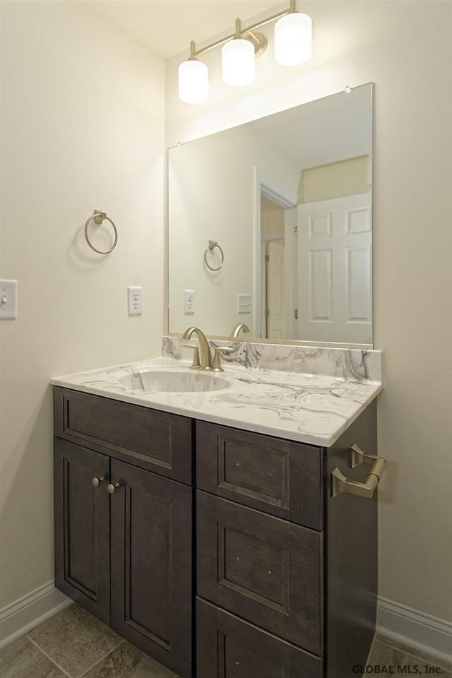 bathroom with baseboards, vanity, and tile patterned flooring