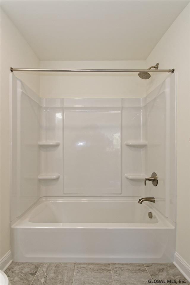 bathroom featuring tile patterned flooring, shower / bathtub combination, and baseboards