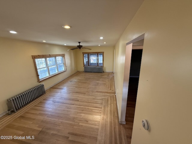 unfurnished room featuring radiator heating unit, light wood-style floors, and recessed lighting