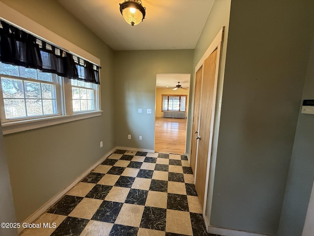 hall featuring plenty of natural light, dark floors, and baseboards