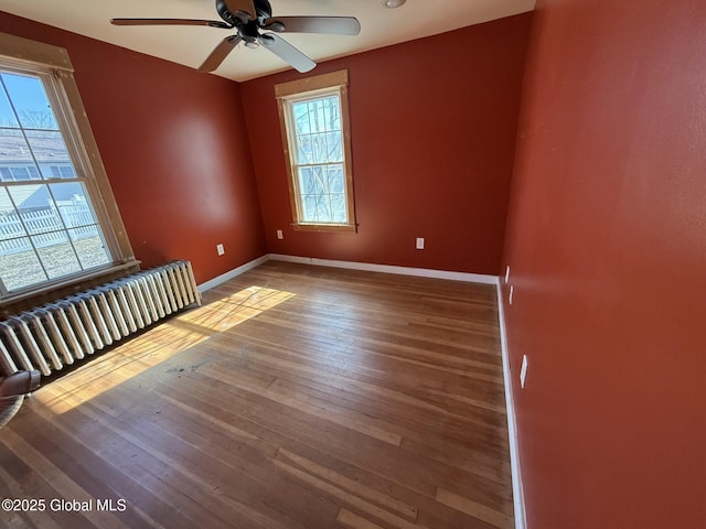 spare room featuring baseboards, wood-type flooring, and a ceiling fan