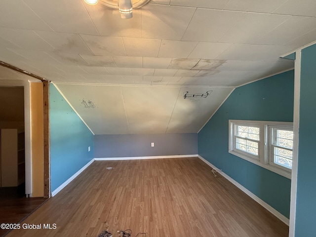 additional living space with baseboards, lofted ceiling, and wood finished floors